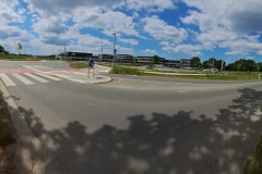 Panorama - Harsefelder Straße Panoramaaufnahme eines modernen Kreisverkehrs mit neu angelegtem Radweg und Zebrastreifen an der Harsefelder Straße in Stade. Links und rechts verlaufen separate Geh- und Radwege, im Hintergrund moderne Gebäude, Autos und offene Landschaft.