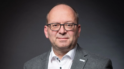 Portraitfoto von Bürgermeister Sönke Hartlef vor einem dunklen Hintergrund