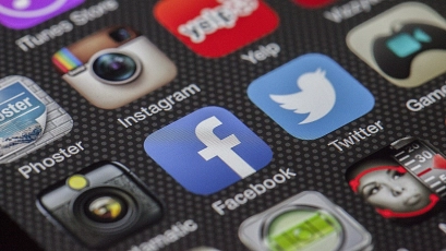 Zu sehen ist der Bildschirm eines Smartphones, auf dem unterschiedliche App-Symbole dargestellt sind: u.a. Facebook und Twitter