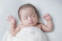 Symbolbild - Neugeborenes, Baby, Geburt Schlafendes Neugeborenes liegt auf einer weißen Unterlage und ist mit einer weißen Decke zugedeckt